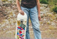 picture of a person holding a skateboard, standing on a road