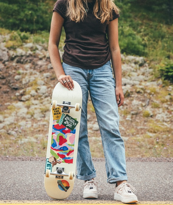 picture of a person holding a skateboard, standing on a road