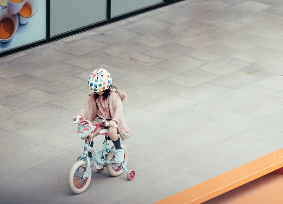 picture of a kid riding a bike outside wearing super cool helmet 