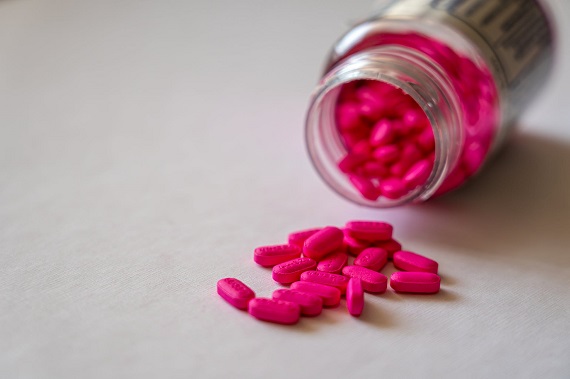 picture of pink pills spilled of the box  on a white surface 