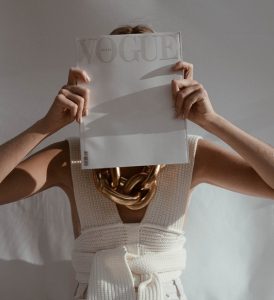 picture of a woman in white top holding a paper in front her face