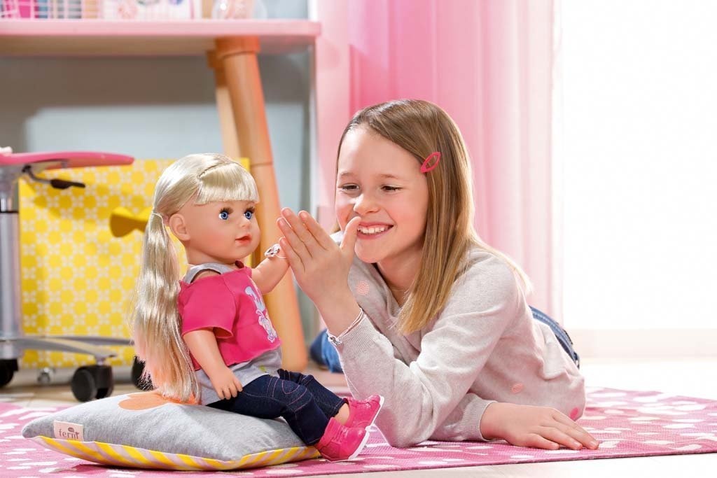 girl smiles with her doll toy in her room