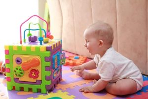 infant baby toys plaing on a floor