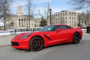 A sleek red sports car parked in front of a historical building with a golden dome.