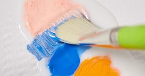 paintbrush mixing acrylic paint and acrylic medium