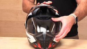 Person holding an HJC full-face motorcycle helmet, showcasing the helmet's visor and aerodynamic design.